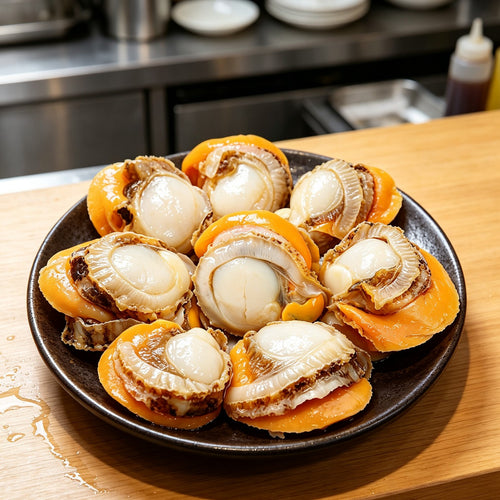Half-shell scallops with orange roe plated on a white dish