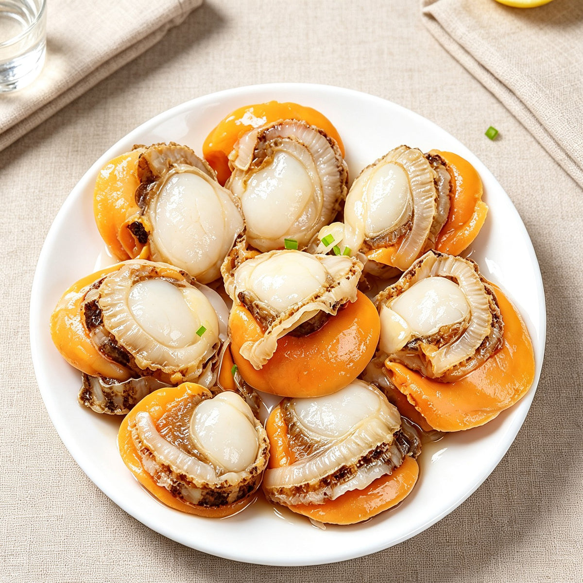 Half-shell scallops with orange roe plated on a white dish